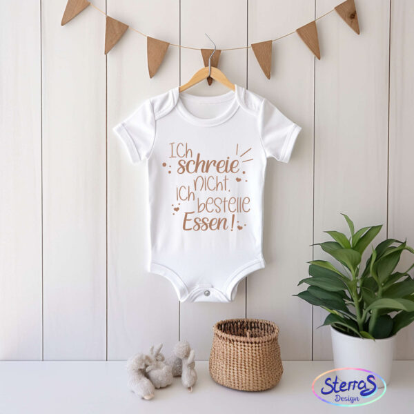 Weißer Babybody mit dem Design in hellem braun hängend an einer Girlande. Unten im bild sind noch Blumen und ein wenig Deko dargestellt. Minimalistisch und ruhig gestaltet.