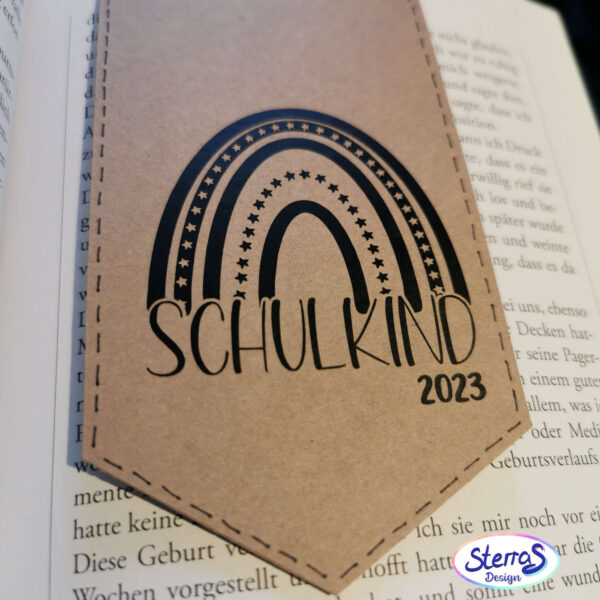 Anwendungsbeispiel: Motiv „Schulkind“ mit einem Regenbogen in Schwarz geplottet auf einem Lesezeichen aus Kraftkarton. Darunter das Jahr „2023“ als Einschulungsjahr. Schlicht und modern.