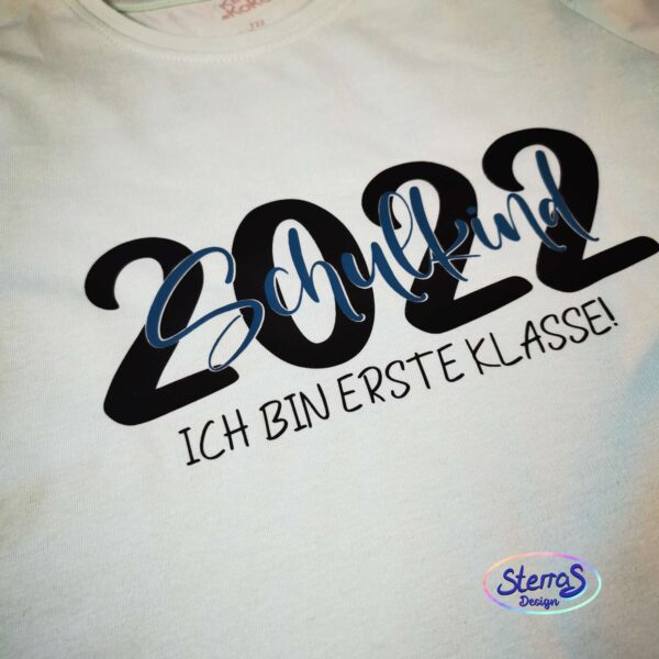 Plottermotiv „2022 – Ich bin erste Klasse“ in Schwarz, präsentiert auf weißem Shirt. Klarer, kontrastreicher Stil – ideal für Shirts oder Schultüten.
