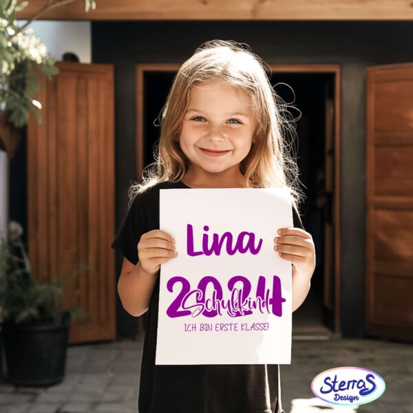 Mädchen mit Namensschild „Lina 2024“ in Pink-Lila, präsentiert ein Plakat. Ideal als Mockup zur Personalisierung von Einschulungsschildern oder Shirts.