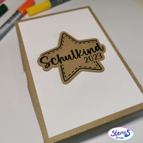 kleine Box aus Kraftkarton zum verschenken. Auf der Box ist ein Stern mit der Datei "Schulkind 2023" in einem Sternenrahmen in schwarz zu sehen.