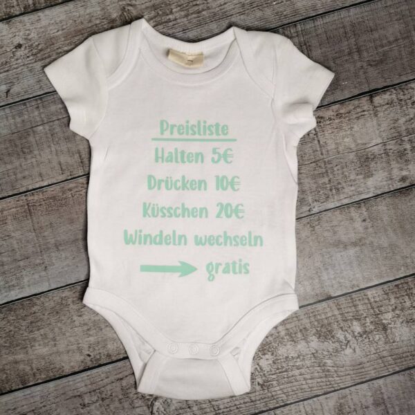Weißer Babybody auf Holzhintergrund mit witziger Preisliste in hellem Blau: „Halten 5 €, Drücken 10 €, Küsschen 20 €, Windeln wechseln: Gratis“. Ideal als Geschenk zur Geburt mit Augenzwinkern.