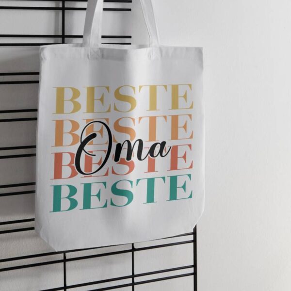 Der Spruch „Beste Oma“ ist auf einem hellen Leinbeutel geplottet. Der Beutel hängt dekorativ an einer Wand.