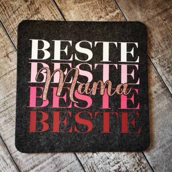 Nahaufnahme des Designs „Beste Mama“ auf einem größeren Filzuntersetzer, geplottet in Rosé-Glitzerfolie in rot-rosa Farbtönen.