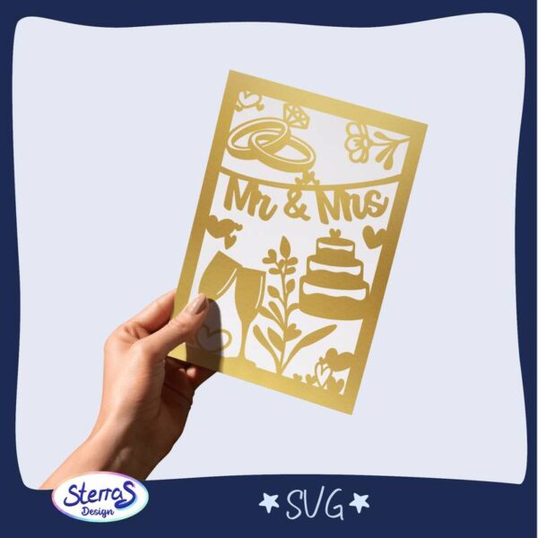 Digitale Basteldatei für Hochzeitskarte mit ausgestanzten Symbolen (Torte, Ringe, Blumen). Foto zeigt goldene Papierkarte in Hand gehalten. Umgeben von blauem Rahmen, SVG-Datei, SterrasDesign-Logo unten links.