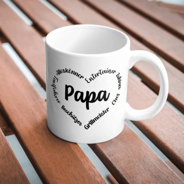 Weiße Tasse mit Herzmotiv und Schriftzug "Papa", stehend auf einem Holztisch im Freien. Die Datei wurde zur Personalisierung der Tasse verwendet.