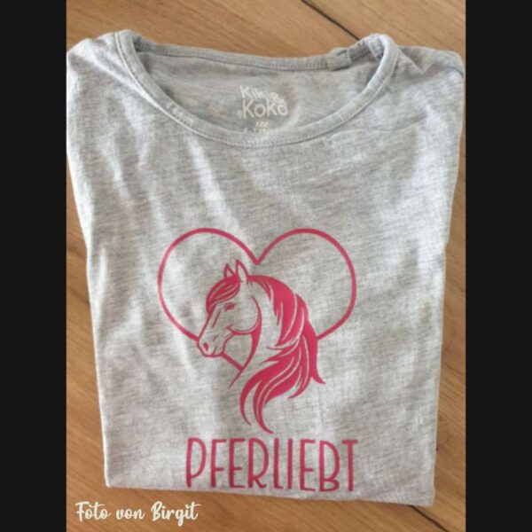 Graues T-Shirt mit geplottem Motiv: Pferdesilhouette mit Herz, daneben der Text „pferliebt“. Dezent und klar lesbar, aufgenommen bei natürlichem Licht.